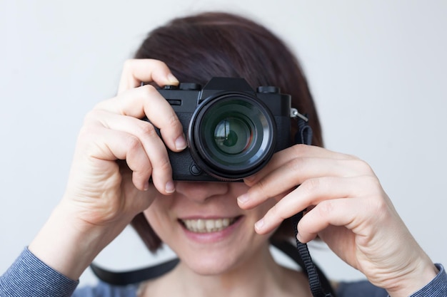 Une fille tient un appareil photo près de son visage L'objectif ressemble à un grand œil Passe-temps avec la photographie