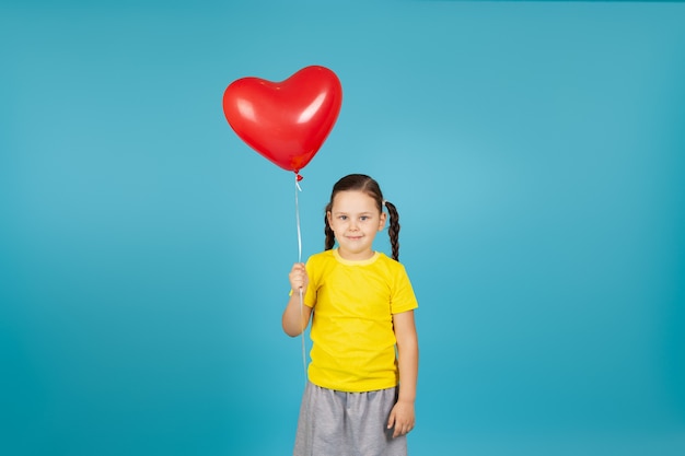 fille tient un ballon rouge volant en forme de coeur