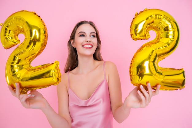 La fille tient des ballons en aluminium sous la forme de nombres de vingt-deux pour cent de remises sur les ventes et les remises en argent