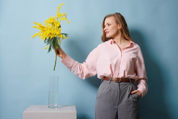 La fille tient une branche de mimose dans sa main et la met dans le concept de source d'eau.