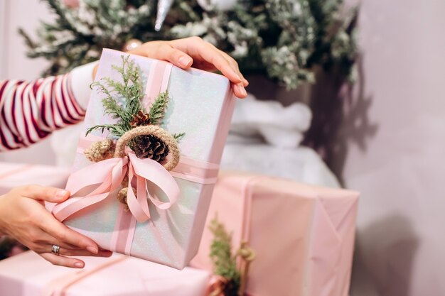 Fille tient un cadeau, arbre de Noël, boîte rose avec un cadeau