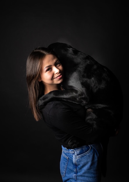 Une fille tient un chien Labrador Retriever dans ses bras