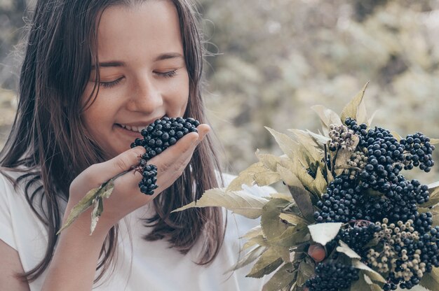 Fille tient dans les mains des grappes de fruits sureau noir dans le jardin