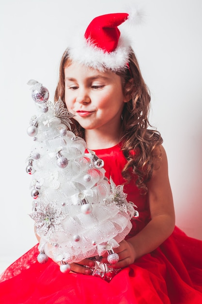 La fille tient dans ses mains un décor fait main - arbre de Noël de ruban d'argent