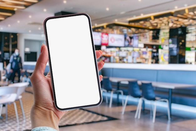 Photo une fille tient dans ses mains une maquette d'un smartphone avec un écran blanc sur fond de supermarché
