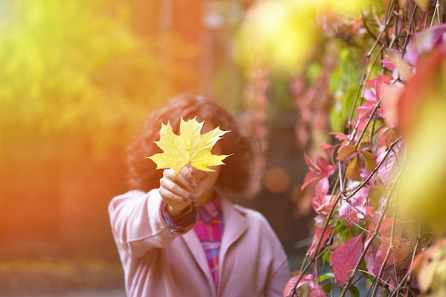 La fille tient une feuille jaune