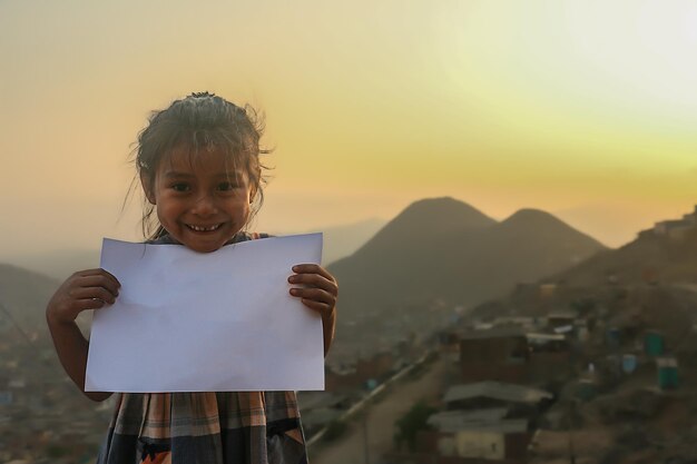 La fille tient une feuille de papier vierge pour insérer un texte ou un message positif ou motivant.