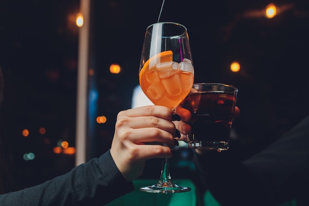 Une Fille Tient à La Main Un Verre Transparent De Cocktail Rouge, Des Glaçons Flottent Dans Le Verre.