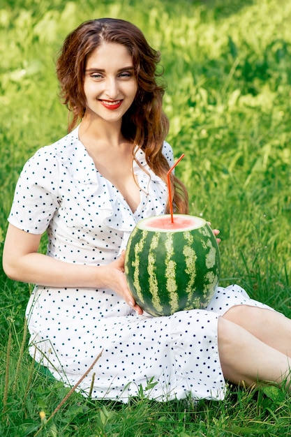 Fille tient la pastèque entière avec de la paille à cocktail