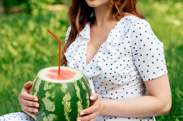 Fille tient la pastèque entière avec de la paille à cocktail