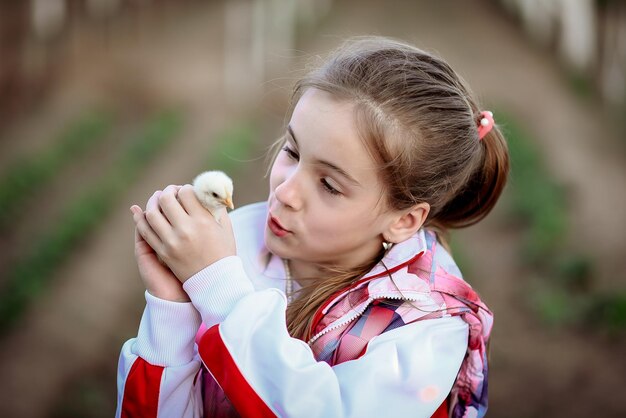Une fille tient un petit poulet dans ses mains