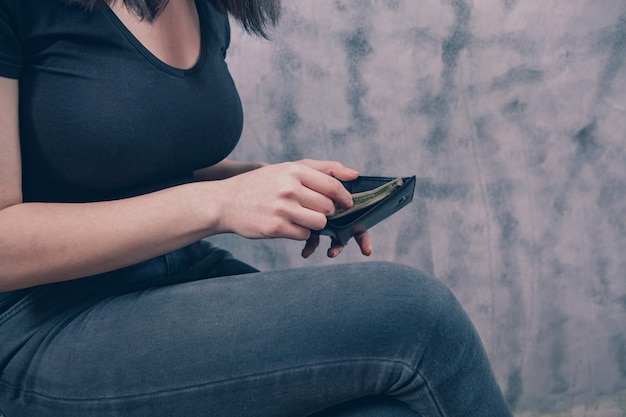 La fille tient le portefeuille dans ses mains et prend de l'argent