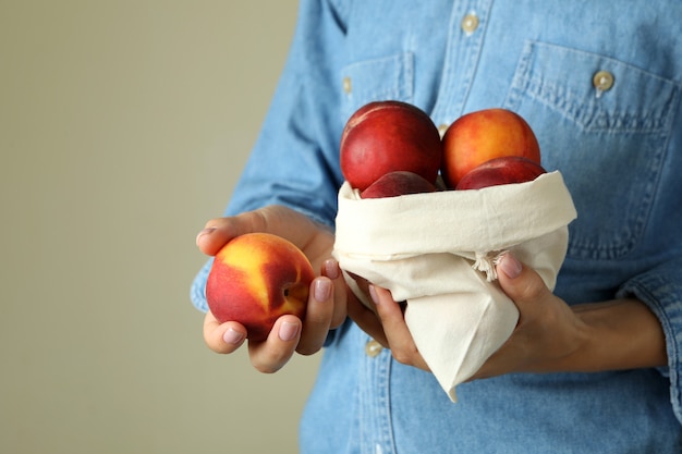 La fille tient le sac avec les fruits mûrs de pêche