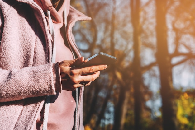 Une fille tient un smartphone moderne dans ses mains et utilise Internet.