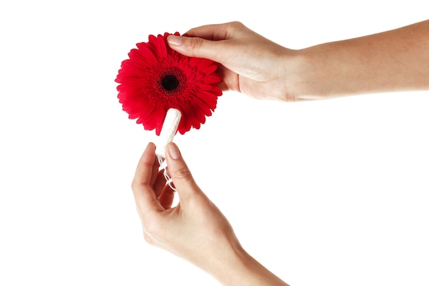 La fille tient un tampon et un gerbera isolés sur un fond blanc. Notion d'ovulation. notion de menstruation.