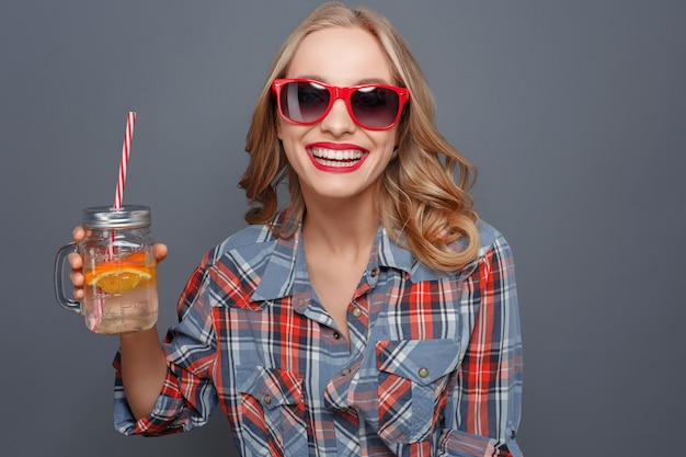 fille tient une tasse avec du jus et un morceau d'orange