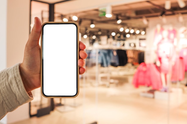 Photo une fille tient un téléphone dans sa main avec un écran isolé vierge sur le fond d'un centre commercial flou