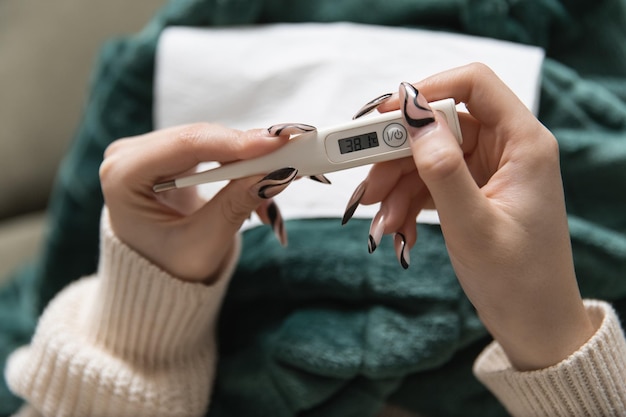 Une fille tient un thermomètre dans ses mains qui indique une température élevée en cas de maladie