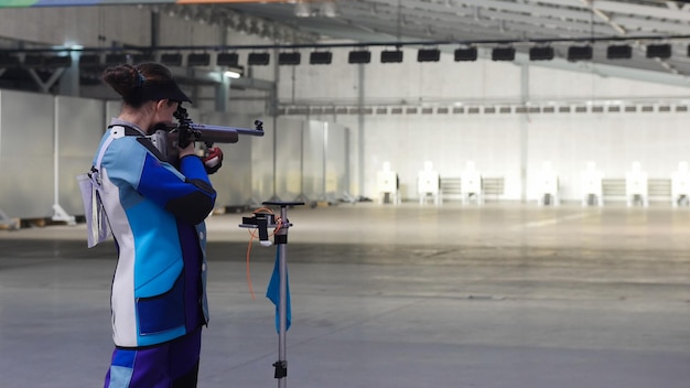 La fille de tir de balle dans un costume bleu vise une cible