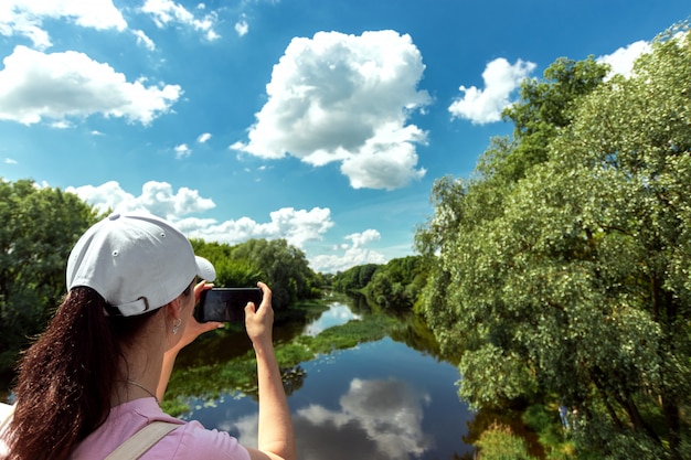 Photo fille tire un beau paysage sur un smartphone