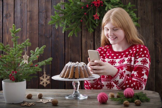 Fille tire le gâteau de Noël sur l'appareil photo du téléphone mobile