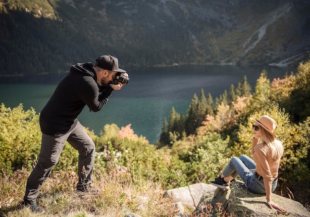 Fille de tourisme posant pour une photo au sommet de la montagne. Photographe prenant des photos d'une jeune fille