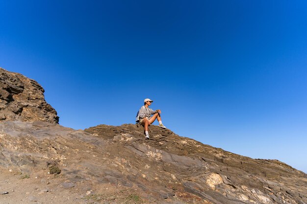 une fille touriste avec un sac à dos se repose en été assise au sommet d'une montagne