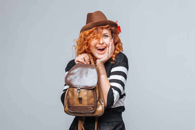 Fille de touriste tête rouge avec sac à dos sur fond gris