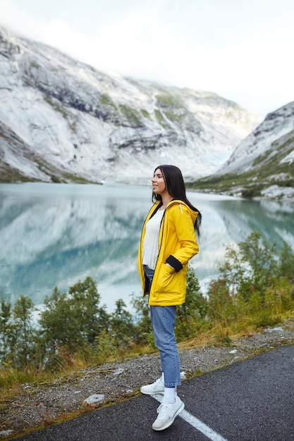 Fille touriste en veste jaune posant sur le lac en Norvège Femme active relaxante en Norvège