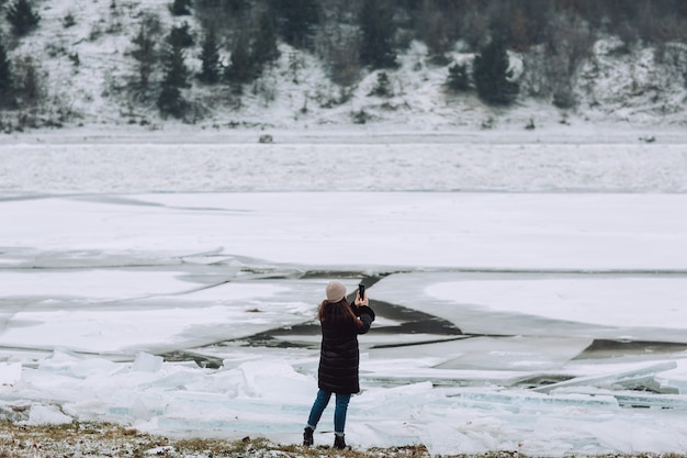 Fille de touriste voyageant sur une rivière gelée et prenant un paysage d'hiver photo. Fille en vacances d'hiver.