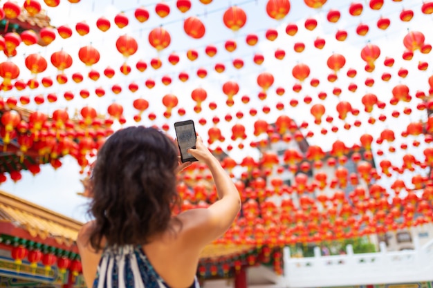 Une fille touristique photographie les décorations du Nouvel An avec des lanternes chinoises du temple chinois