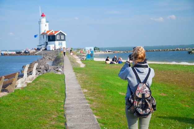 La fille tourne la vidéo au phare sur la mer