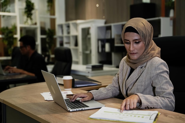 Fille travaillant sur le bureau Femme d'affaires musulmane occupée avec des documents et un ordinateur portable dans un concept d'entreprise de bureau moderne