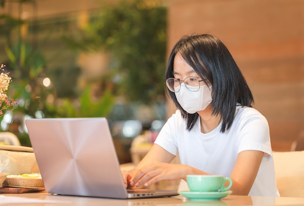 Fille travaillant sur son ordinateur portable Adolescente asiatique tapant sur un ordinateur portable dans un café