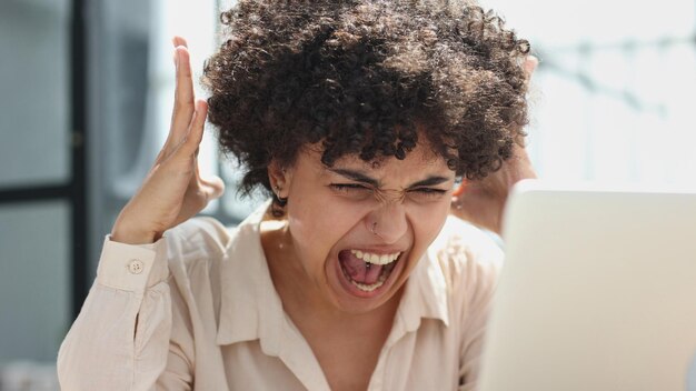 Photo une fille travaille dans un bureau à un ordinateur portable se met en colère exprime son insatisfaction