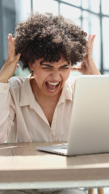 une fille travaille dans un bureau à un ordinateur portable se met en colère exprime son insatisfaction