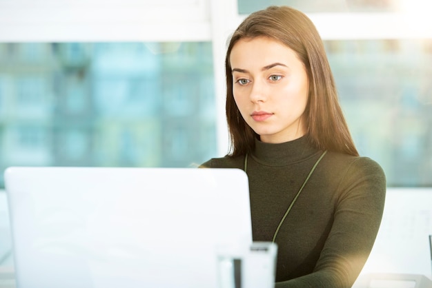 Fille travaille sur un ordinateur portable dans un bureau moderne