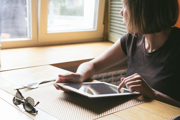 La fille travaille sur la tablette