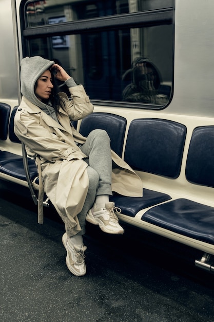 Une fille en trench-coat beige monte dans une rame de métro.