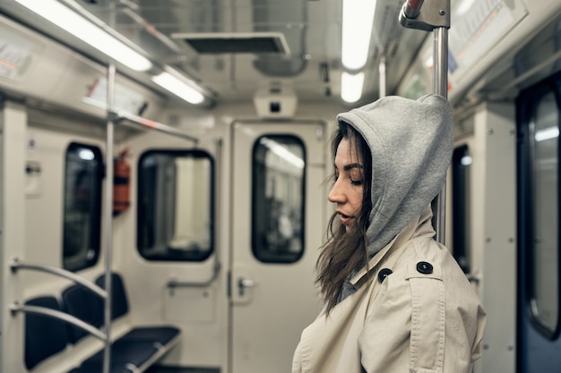 Une fille en trench-coat beige monte dans une rame de métro.