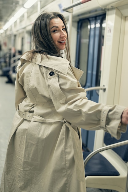 Une fille en trench-coat beige monte dans une rame de métro.