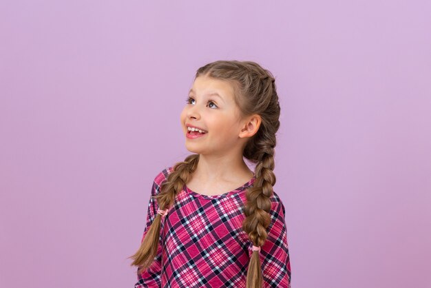 Une fille avec des tresses sur la tête lève les yeux avec joie.