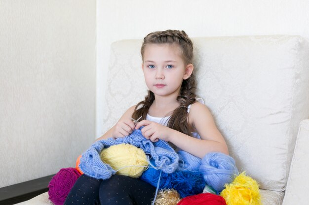 La fille tricote avec du tricot et du fil.