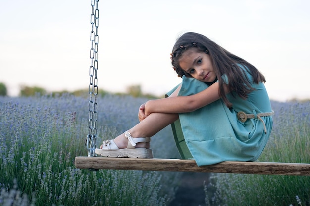 Photo fille triste dans un champ de lavande sur une balançoire