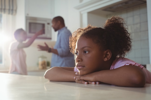 Fille triste écoutant ses parents se disputer dans la cuisine