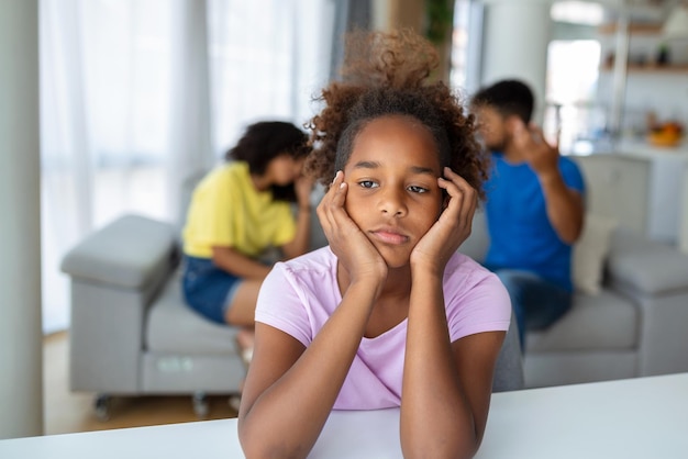 Fille triste écoutant ses parents se disputer dans le salon à la maison