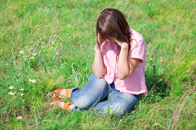 Fille triste à l'herbe verte à la campagne.