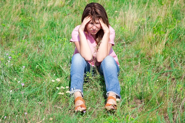 Fille triste à l'herbe verte à la campagne.