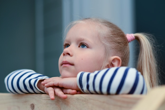 Fille triste romantique sur une balustrade en bois lève les yeux et est triste