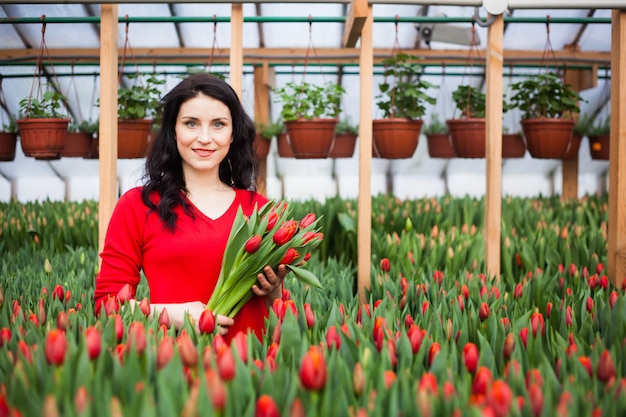 Fille avec des tulipes cultivées dans une serre.